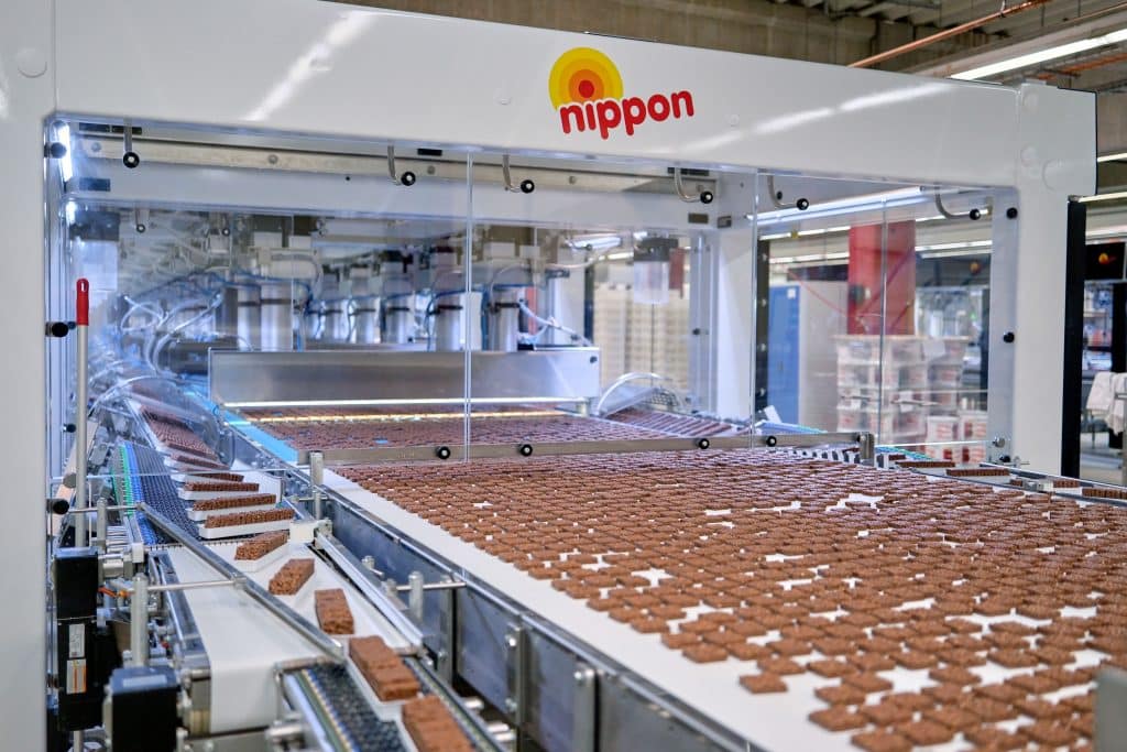 Schoko-Abrieb hat keine Chance: Die Bandreinigungseinheit BeBelt und der Dampfreiniger Blue Evolution XL+ mit Industrieabsaugung von beam sorgen für HACCP-zertifizierte Hygiene in der Produktion der beliebten Puffreis-Schokoladen-Snacks „Nippon“. Foto: Ingo Jensen/beam